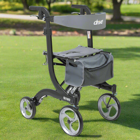Drive Medical Nitro Aluminum Tall Rollator (RTL10266BK-T) shown outdoors on green grass in a park, featuring lightweight black frame, 10-inch wheels, padded seat, and storage bag.