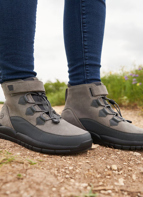 Close-up of gray diabetic walking shoes with adjustable laces and ankle support, worn outdoors on a dirt path—featured in Dahl Medical Supply’s Diabetic Shoes Collection.