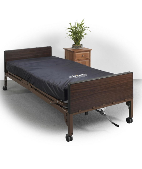 Alt Text: Hospital bed rental from Dahl Medical Supply featuring an adjustable Drive Medical bed with dark wood headboard and footboard, shown with mattress and bedside table.