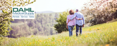Older couple walking together through a sunny meadow, symbolizing comfort, confidence, and independence with incontinence care products from Dahl Medical Supply.