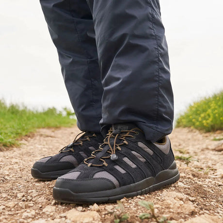 Man wearing dark gray men’s diabetic casual shoes with elastic laces, walking on a gravel path—comfortable, supportive footwear from Dahl Medical Supply.