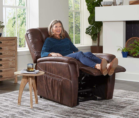 Smiling woman relaxing in a brown lift chair recliner inside a bright living room, demonstrating the comfort and style of lift chair rentals from Dahl Medical Supply.