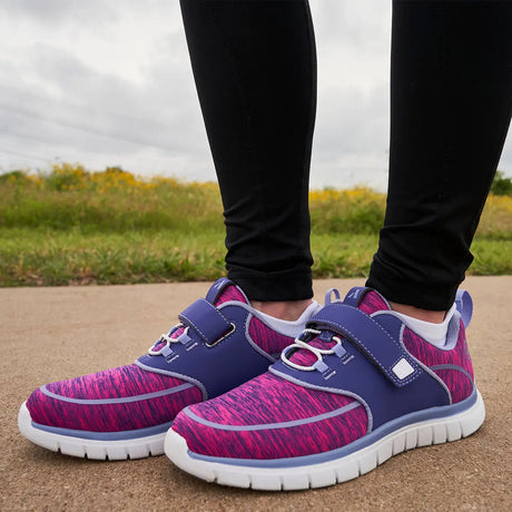 Woman wearing purple and pink diabetic athletic shoes with adjustable strap and cushioned white soles for comfort and foot protection – available at Dahl Medical Supply.