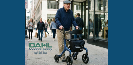 A senior man walking outdoors on a city sidewalk using a blue Drive Medical AeroWalk Ultra-Lite Rollator with seat and storage bag, promoting mobility and independence