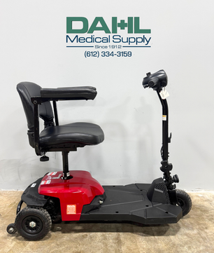 Side view of the Drive BoBCAT X3 3-wheel mobility scooter showing the padded swivel seat, adjustable armrests, compact foot platform, and lightweight frame. Photo taken inside Dahl Medical Supply showroom.