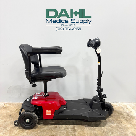 Side view of the Drive BoBCAT X3 3-wheel mobility scooter showing the padded swivel seat, adjustable armrests, compact foot platform, and lightweight frame. Photo taken inside Dahl Medical Supply showroom.