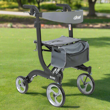Drive Medical Nitro Aluminum Tall Rollator (RTL10266BK-T) shown outdoors on green grass in a park, featuring lightweight black frame, 10-inch wheels, padded seat, and storage bag.