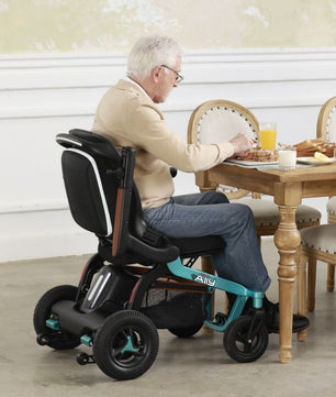 Adult seated in a Golden Ally GP303 portable power wheelchair while dining at a table indoors, showing the compact frame, comfortable seating, and easy maneuverability.