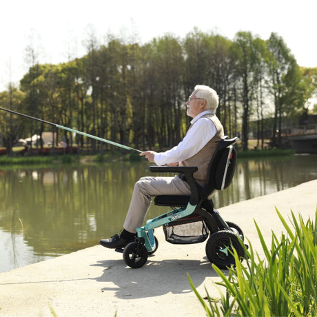 Adult using a Golden Ally GP303 portable power wheelchair while fishing beside a calm lake, with trees and nature in the background.