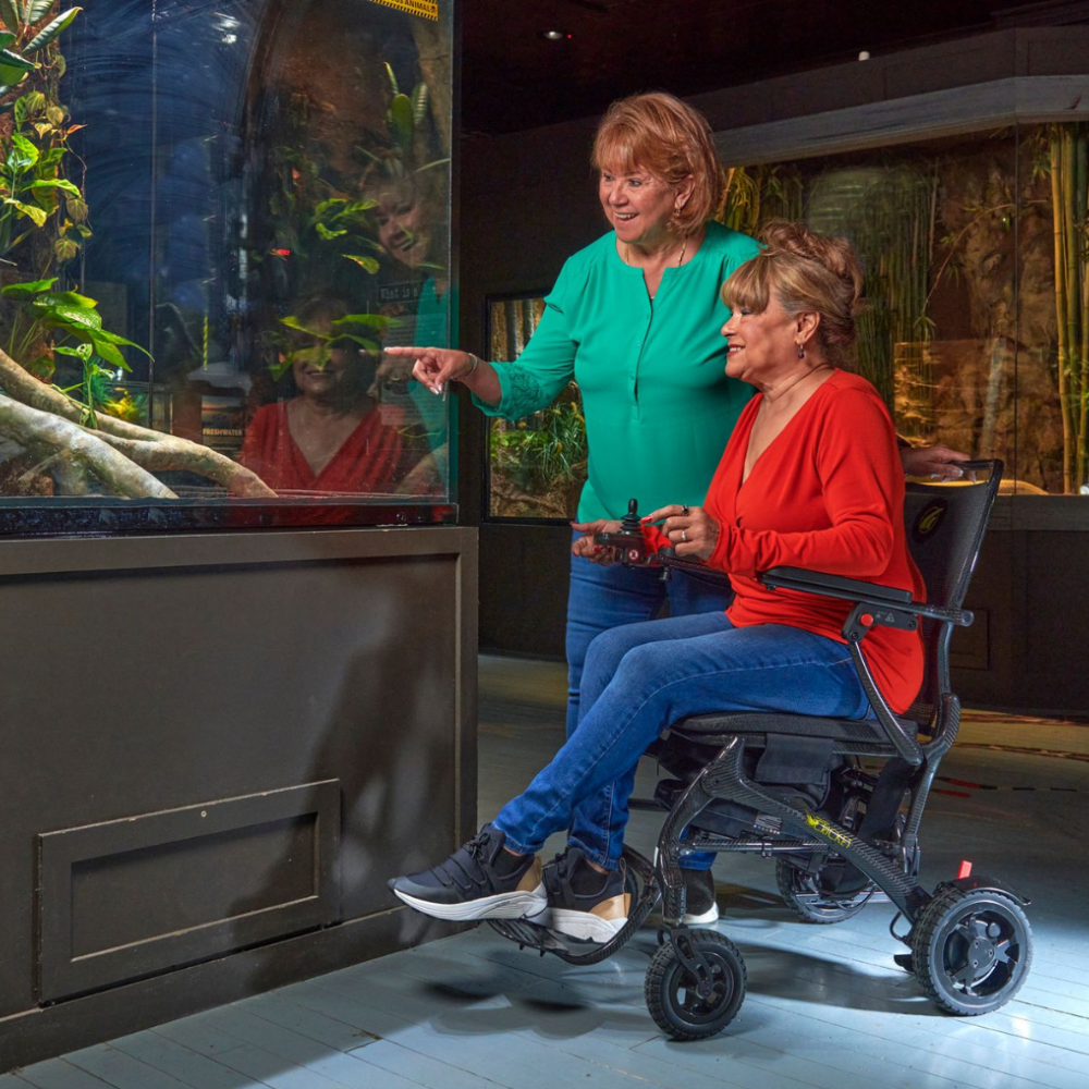 Woman using the Golden Cricket Lightweight PowerChair at an aquarium