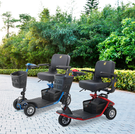 Two Golden LiteRider mobility scooters, one blue 3-wheel and one red 4-wheel, parked on a paved outdoor path with greenery in the background.