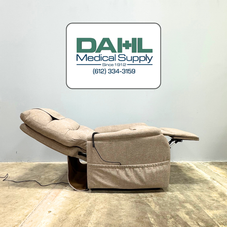 Very lightly used Golden PR118 lift chair shown in a reclined resting position, featuring supportive cushioning, extended footrest, and neutral fabric. Photo taken at Dahl Medical Supply showroom in Minnesota.