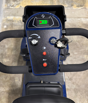 Close-up view of the mobility scooter tiller controls, including speed dial, battery indicator, and control buttons, shown on a used 4-wheel scooter.