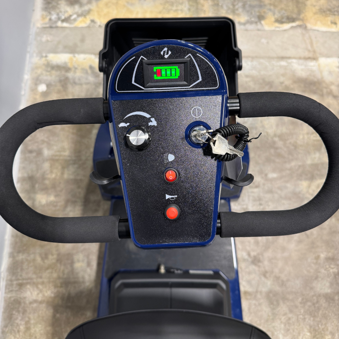 Close-up view of the mobility scooter tiller controls, including speed dial, battery indicator, and control buttons, shown on a used 4-wheel scooter.