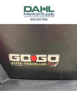 Close-up view of the battery compartment on a used Pride Go Go Elite Traveller Plus 3-wheel mobility scooter, showing the Go Go Elite Traveller Plus branding.