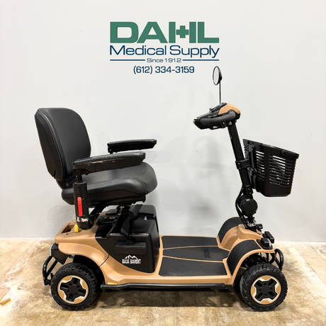 Side profile of a used Baja Bandit 4-wheel mobility scooter showing wide foot platform, adjustable seat with armrests, heavy-duty wheels, and stable outdoor-ready design from Dahl Medical Supply.