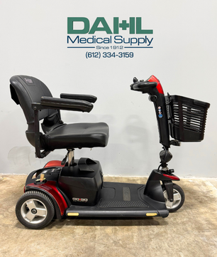 Side view of a used Pride Go Go Elite Traveller Plus 3-wheel mobility scooter with padded seat, armrests, front basket, and compact frame, photographed at Dahl Medical Supply.