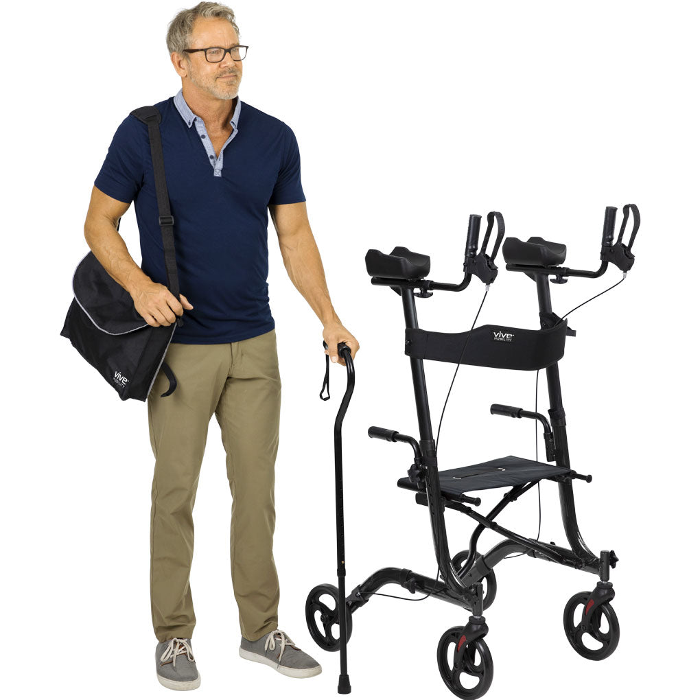 Man standing next to a folded Vive Upright Rollator Walker, holding a cane and carrying the included storage bag over his shoulder. Lightweight, portable, and easy to transport – available at Dahl Medical Supply for $225.