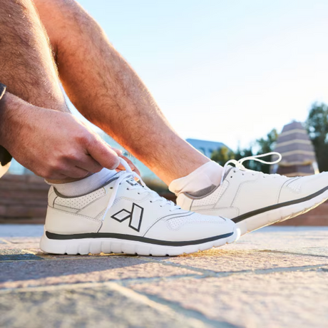 Man tying white Anodyne No. 50 diabetic athletic shoes outdoors, showcasing comfort and support for active daily wear.