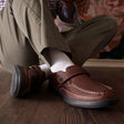 Man seated on hardwood floor wearing the Anodyne No. 52 Whiskey Brown casual diabetic shoe with adjustable Velcro strap – comfortable orthopedic footwear from Dahl Medical Supply.